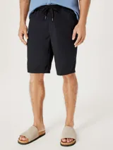 Bermuda de corte recto en color negro, confeccionada en tejido de algodón, con cierre frontal y bolsillos laterales.