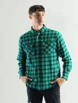 Camisa de franela a cuadros verdes, negros y rojos, de manga larga, con cuello abotonado y dos bolsillos con solapa abotonada en el pecho.