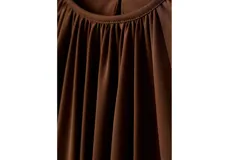 Blusa de color marrón chocolate con cuello redondo, diseño fruncido en la parte superior y mangas largas abullonadas con puños elásticos.