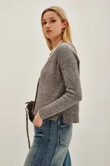 Cardigan de tejido de punto color beige melange, con escote en V y cierre frontal de botones plateados. Presenta mangas largas con puños acanalados.