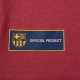 Camiseta deportiva color borgoña con cuello redondo y mangas cortas. Estampado en el pecho con el escudo del FC Barcelona y la palabra "Barça" en azul.
