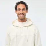 Buzo de felpa color blanco crudo, con capucha ajustable mediante cordones, cierre frontal parcial en el cuello y bolsillo tipo canguro. Presenta puños y ruedo acanalados.