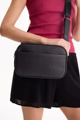 Bandolera Aurea de poliuretano símil cuero color negro, con diseño rectangular y bolsillo frontal externo. Cuenta con cierre superior y correa ajustable.