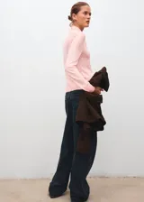 Jersey de punto fino color rosado, con cuello alto y detalle de nudo en el cuello.