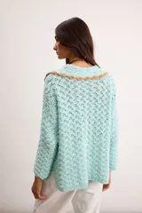 Saco de hilo de algodón tejido a crochet en color celeste, con diseño abierto, mangas largas y cuello romántico con detalles en tono tostado y cierre superior de botón.