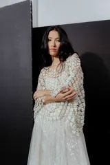 Blusa de red en color blanco con apliques de flores tridimensionales en toda la prenda. Presenta transparencias, cuello redondo y mangas largas.