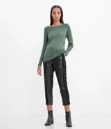 Suéter de punto color rosado, con cuello barco, mangas largas y puños con botones decorativos. El dobladillo también es acanalado.