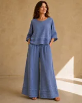 Blusa de lino color azul jean, con cuello redondo, mangas amplias tres cuartos y detalle de volado fruncido en el ruedo.