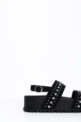Sandalia chunky de plataforma color negro, con diseño de doble tira ancha decorada con tachas metálicas cónicas y pulsera ajustable al tobillo con hebilla.