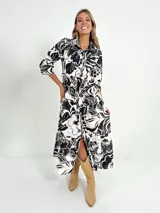 Vestido camisero midi de manga 3/4 con estampado floral en blanco y negro. Tiene cuello camisero, cierre frontal con botones y cinturón.