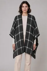 Ruana abierta con diseño de cuadros en tonos gris y blanco, con bordes terminados en color negro.