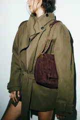 Bolso de hombro confeccionado en piel de ante color marrón, con diseño de pespuntes geométricos en la solapa. Cuenta con una correa de cadena metálica dorada y cierre imantado.