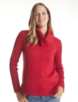 Buzo de punto color beige con cuello volcado amplio, mangas largas acanaladas y torso liso. Presenta una costura central vertical, ruedo con tajos laterales y largo asimétrico, siendo más largo en la parte posterior.