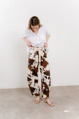 Pantalón ancho de lino con estampado de manchas de vaca en tonos marrón y blanco. Incluye cinturón de soga trenzada con flecos.
