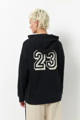 Canguro beige de algodón con capucha, manga larga y estampado frontal con la leyenda "Sport Club 23". También tiene estampado en las mangas.