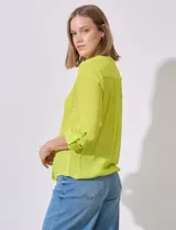 Blusa color amarillo de gasa marca Zac & Rachel, con cuello a la base, escote en V y abertura central con botones. Delantera con bolsillo aplicado. Largo de manga regulable con presilla y botón. Terminación opcional de nudo en ruedo.