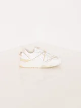 Zapatilla urbana color blanco con detalles en cuero color crema, con cordones y suela de goma.