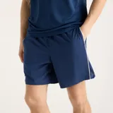 Short deportivo New Balance modelo Tournament, color azul marino, con cordón ajustable en la cintura y logo blanco en la pierna.