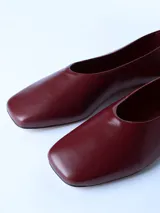 Zapato tipo ballerina de cuero color bordó, con punta cuadrada y suela plana.