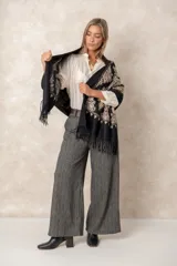 Pashmina de tela densa y suave, con caída pesada y diseño bordado con motivos florales en tonos dorados y beige. Presenta terminaciones con flecos en los extremos.