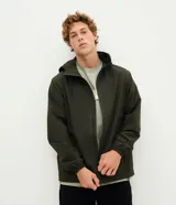 Campera rompevientos verde militar de microfibra, con capucha ajustable con cordón, cierre frontal por cremallera y bolsillos laterales con cierre. Presenta puños elásticos.