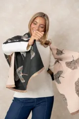 Pashmina reversible de textura suave y caída fluida, con diseño estampado de hojas de ginkgo biloba. Presenta un lado con fondo oscuro y otro con fondo claro, finalizando en ambos extremos con flecos cortos deshilachados.