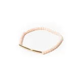 Pulsera elástica con mostacillas facetadas color rosa claro y barrita central de metal dorado.