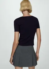 Buzo de punto fino color negro, con cuello redondo y mangas cortas. Presenta un diseño entallado y recto.