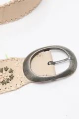 Cinturón de cuero beige con aplicaciones de rafia trenzada y diseño floral bordado. Cuenta con hebilla ovalada de metal envejecido y cierre regulable.