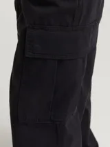 Pantalón cargo negro de pierna ancha con fit amplio y tiro medio alto. Cuenta con bolsillos delanteros, traseros y laterales, además de puños ajustables con cordón.