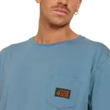 Remera azul de corte recto, manga corta y cuello redondo. Tiene un bolsillo en el pecho con etiqueta de la marca Volcom.