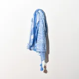 Pashmina rectangular de algodón color celeste con estampado de manchas blancas y terminaciones con flecos.