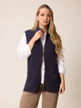 Chaleco de punto en color azul marino, con cierre frontal completo de doble cursor metálico, cuello alto y dos bolsillos frontales tipo parche.