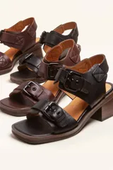 Sandalias de cuero negro con taco bloque de madera tallada, tiras con hebillas grandes y punta cuadrada.