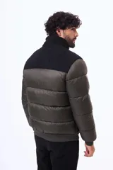 Campera puffer negra con paneles de textura tipo corderito en la parte superior del pecho y hombros. Cuenta con cierre frontal, puños y ruedo acanalados, y un bolsillo vertical con cierre en el pecho.