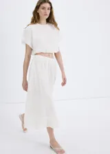 Falda midi evasé de color blanco, confeccionada en algodón con detalles bordados tonales, cintura elástica y forro interior.