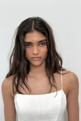 Top crop corsetero negro de popelín con escote recto, tirantes finos ajustables con lazada y bajo acabado con volante. Tiene forro interior a tono y cierre de cremallera en la espalda.