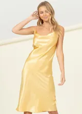 Vestido corto de satén color dorado con cuello drapeado y breteles finos. Presenta un corte recto y fluido, ideal para eventos formales o nocturnos.
