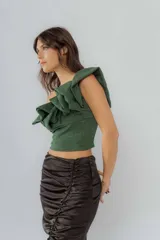 Top corto marrón con brillos, de un solo hombro y volados grandes en el escote.