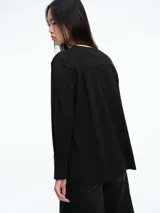 Top de manga larga color blanco con cuello redondo, diseño holgado y tajos laterales en el ruedo.