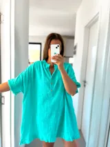 Túnica turquesa de lino con cuello mao, mangas cortas y ruedo desflecado.