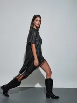Vestido corto de efecto cuero color negro, de corte recto y holgado, con mangas corta y detalle de encaje negro en el dobladillo asimétrico.