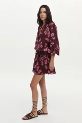 Blusa bordó con estampado floral en tonos rosados, confeccionada en algodón Swiss Dot, con mangas largas abullonadas y escote en V con botones frontales.