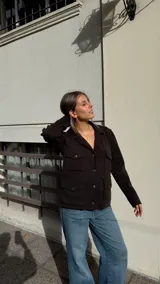 Chaqueta de tejido de punto color marrón oscuro, con cuello solapa, cierre frontal de botones y cuatro bolsillos delanteros con solapa.