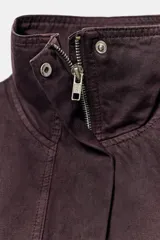 Cazadora de cuello alto y manga larga en color bordó. Presenta cierre frontal con cremallera y botones a presión ocultos bajo solapa, bolsillos laterales de vivo y bajo con acabado elástico.