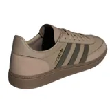 Championes Adidas modelo Handball Spezial, de diseño retro inspirado en los años 70. Confeccionados en una combinación de gamuza y cuero en tonos marrones, presentan las icónicas tres bandas laterales en un tono más oscuro, detalle de logo dorado en el lateral y suela de caucho color caramelo.