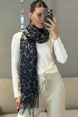 Bufanda rectangular con estampado animal print de leopardo en tonos marrones y negros, con terminación de flecos en los extremos.