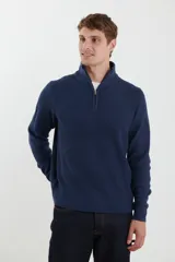 Sweater verde de punto inglés con cuello alto y cierre metálico frontal. Tiene mangas largas y terminaciones en punto canalé.