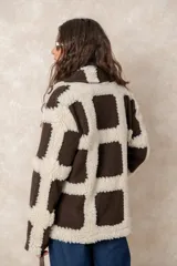 Chaqueta oversize con diseño de cuadros en relieve, confeccionada en una combinación de lana y poliéster con textura tipo borreguillo. Presenta un corte holgado, cuello con solapas y un botón joya central.