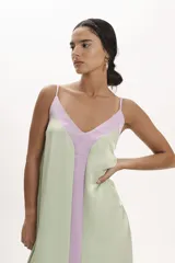 Vestido midi de satén con diseño bicolor en tonos verde agua y lila. Presenta un corte holgado, escote en V con tirantes finos y una franja central vertical en color lila que contrasta con el cuerpo del vestido.